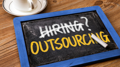 hiring or outsourcing concept handwritten on blackboard